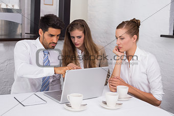 Business people using laptop together at office desk
