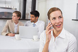 Businesswoman using mobile phone with colleagues at office desk