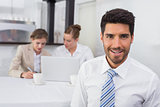 Smiling businessman with colleagues at office desk
