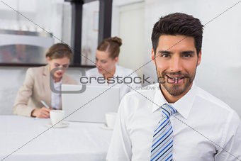 Smiling businessman with colleagues at office desk