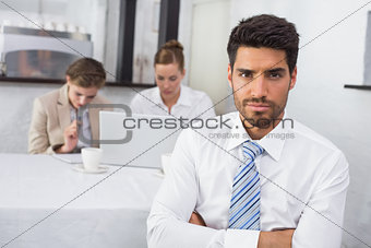 Confident businessman with colleagues at office desk