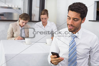 Businessman text messaging with colleagues at office desk