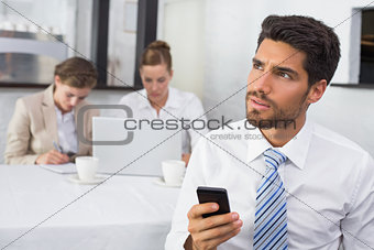 Businessman text messaging with colleagues at office desk