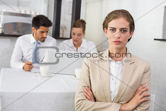 Confident businesswoman with colleagues at office desk