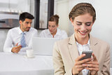 Businesswoman text messaging with colleagues at office desk