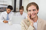 Businesswoman using mobile phone with colleagues at office desk