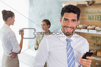 Businessman holding mobile phone in office cafeteria
