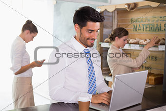 Businessman using laptop in office cafeteria