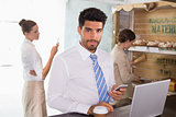 Businessman using mobile phone and laptop in office cafeteria