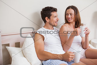 Relaxed couple having coffee in bed