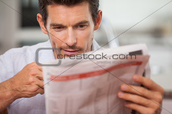Concentrated young man reading newspaper