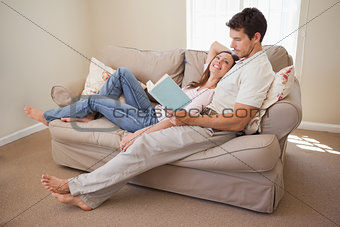 Relaxed young couple reading book on couch