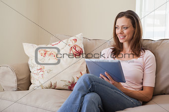 Smiling woman using digital tablet in living room