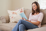 Smiling woman reading book in living room