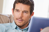 Man with digital tablet looking away at home