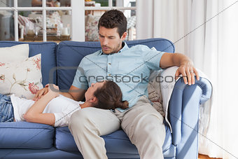 Young woman resting on mans lap on couch