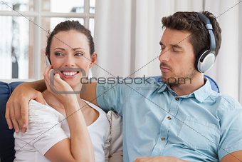 Couple with mobile phone and headphones in living room