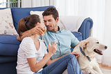 Couple with wine glasses and pet dog in living room