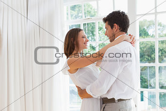Side view of loving couple embracing at home