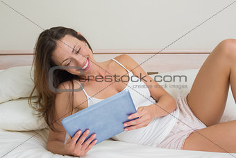 Smiling relaxed woman using digital tablet in bed