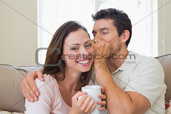 Man whispering secret into a womans ear in living room