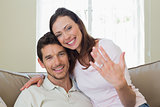 Happy woman showing engagement ring besides man