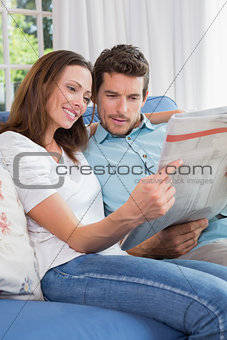 Relaxed couple reading newspaper on couch