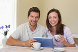 Happy couple using digital tablet while having coffee