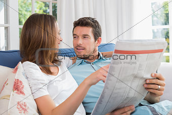 Relaxed happy couple reading newspaper on couch