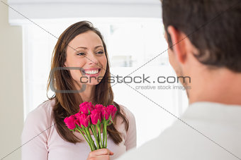Cheerful woman looking at man with flowers
