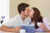 Couple kissing while using digital tablet