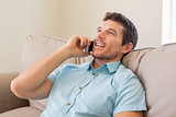 Relaxed man using mobile phone in living room