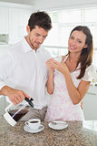 Happy young couple having coffee in kitchen