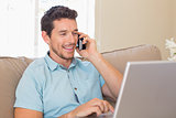 Happy man using laptop and mobile phone on couch