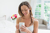 Relaxed woman with coffee cup sitting in bed