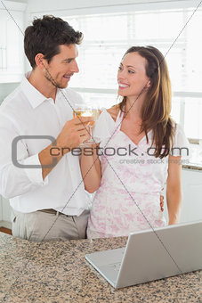 Loving couple toasting wine glasses in kitchen