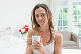 Relaxed young woman with coffee cup in bed