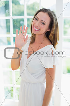 Smiling woman waving hand at home