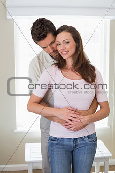 Loving young man embracing woman from behind