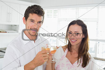 Loving couple toasting wine glasses in kitchen