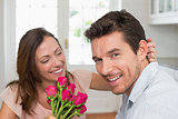 Cheerful woman looking at man with flowers