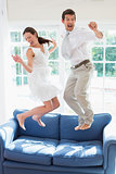 Cheerful young couple jumping on couch