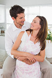Loving man embracing woman from behind at home