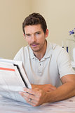 Young man reading newspaper at home