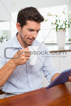 Man using digital tablet while having coffee at home