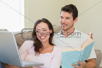 Couple with laptop and book sitting on couch