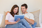 Relaxed couple using digital tablet in living room