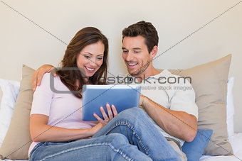Relaxed couple using digital tablet in living room