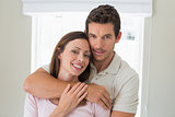 Loving man embracing woman from behind at home