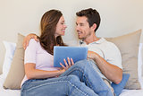 Happy relaxed couple using digital tablet in living room